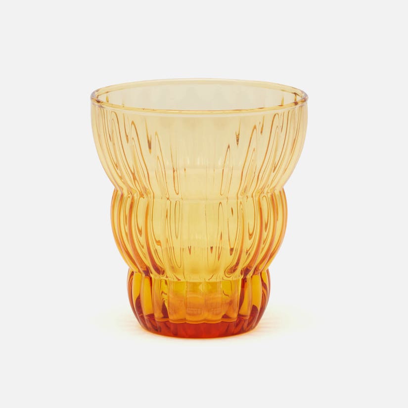 Amber glass tumbler with textured design on a white background