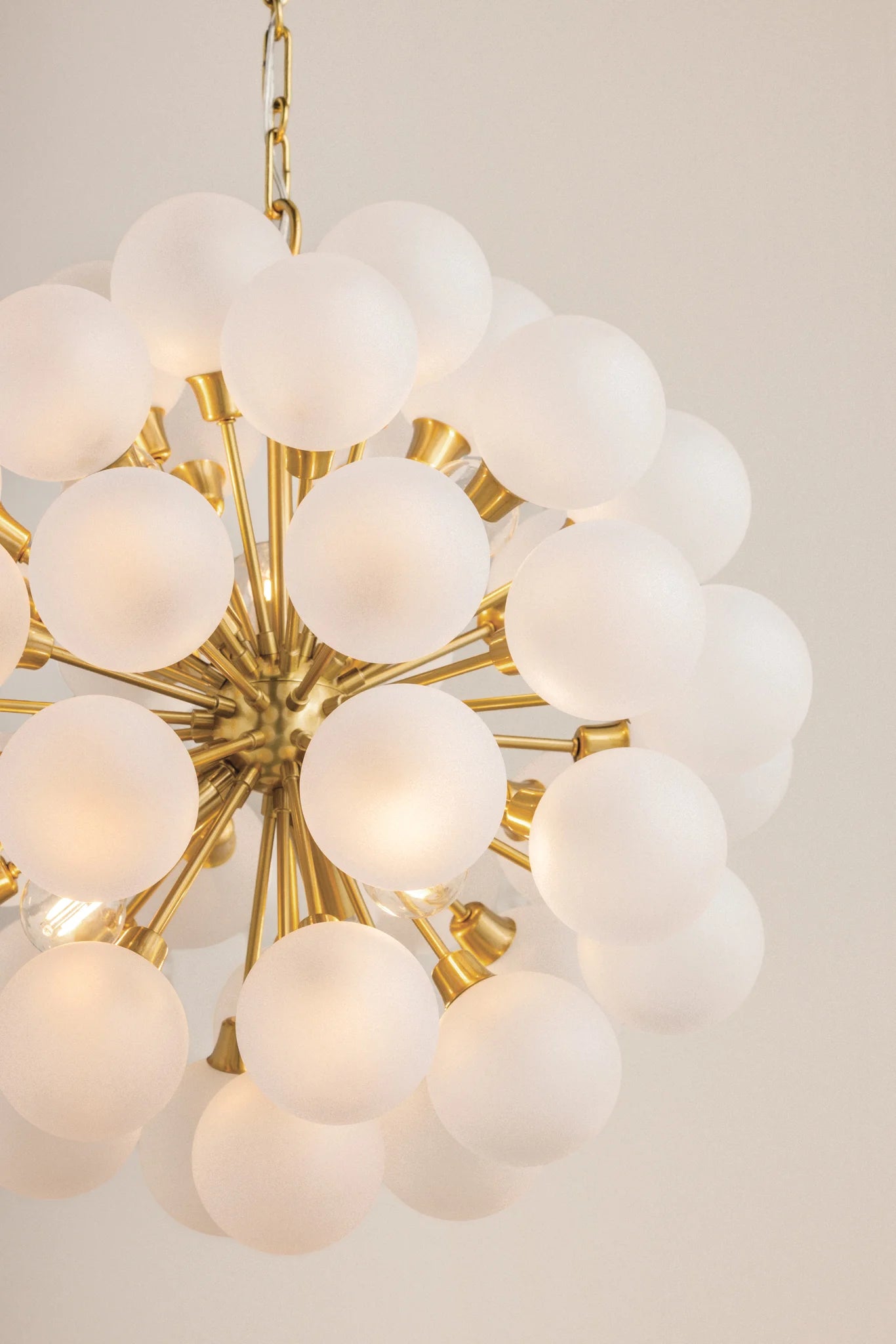 Gold chandelier with white glass globes on a light background