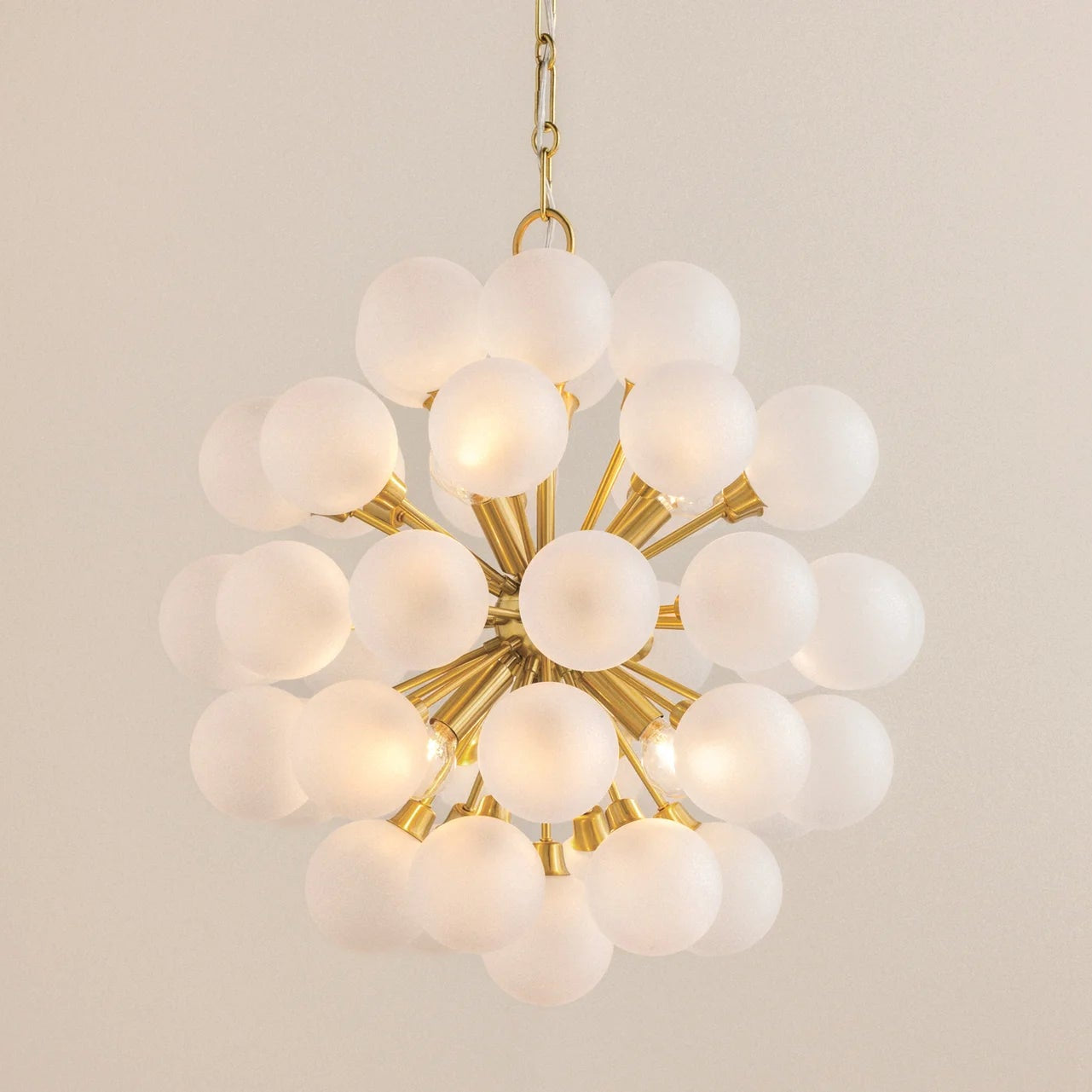 Modern chandelier with gold frame and white glass spheres on a beige background