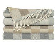 Folded plaid blankets in gray, beige, and white on a white background