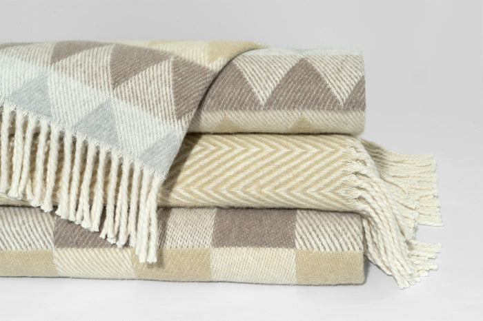 Cintia Throw by D.V. KAP Home, folded and stacked, buffalo check in sage and oat