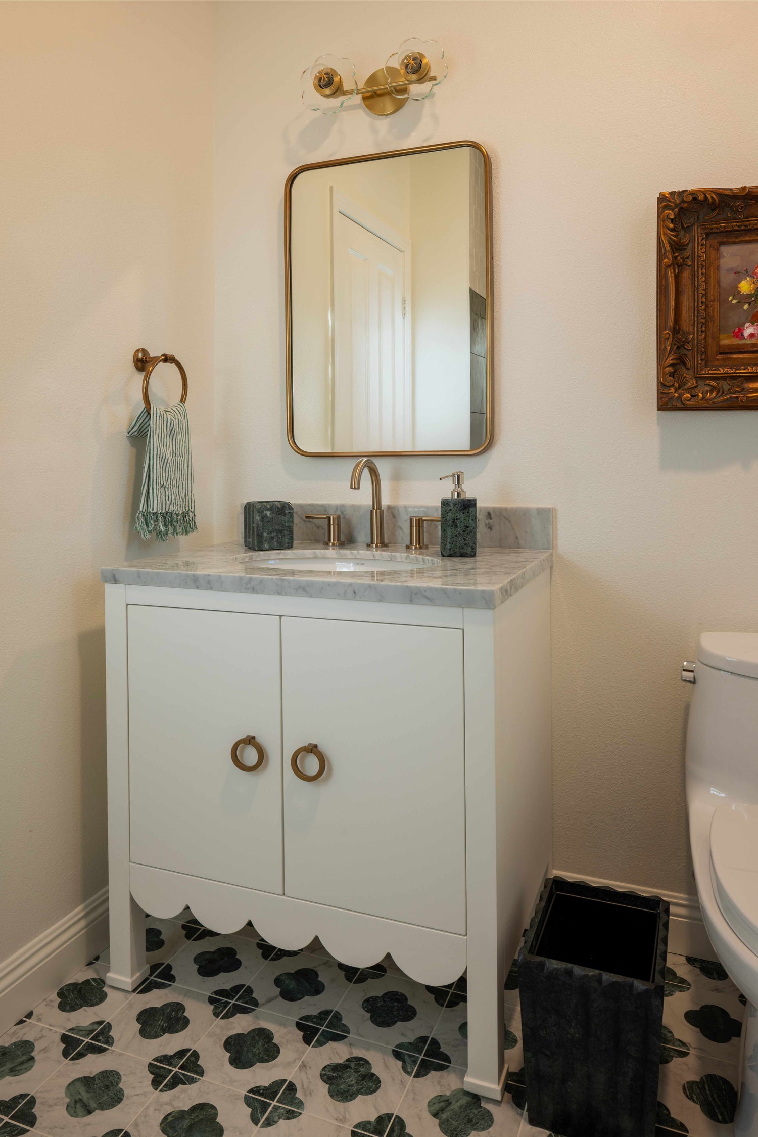 Bathroom with a white vanity, mirror, and toilet with a geometrical tile floor. 