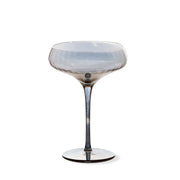 Decorative stemmed coupe glass with a white and gray smoke iridescent color  on a white background