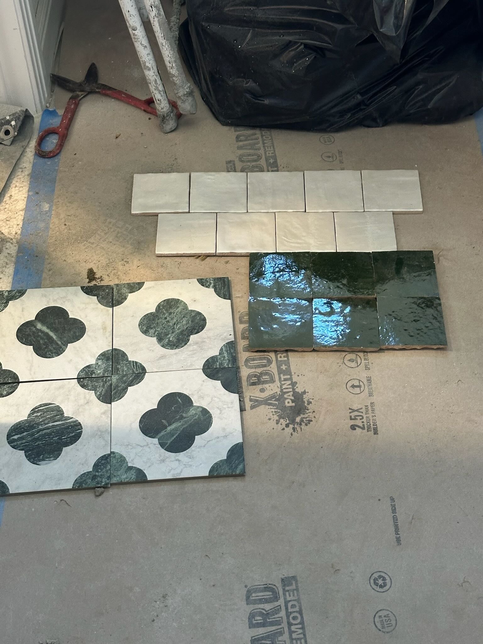 Collection of tiles on a floor with tools and materials in the background