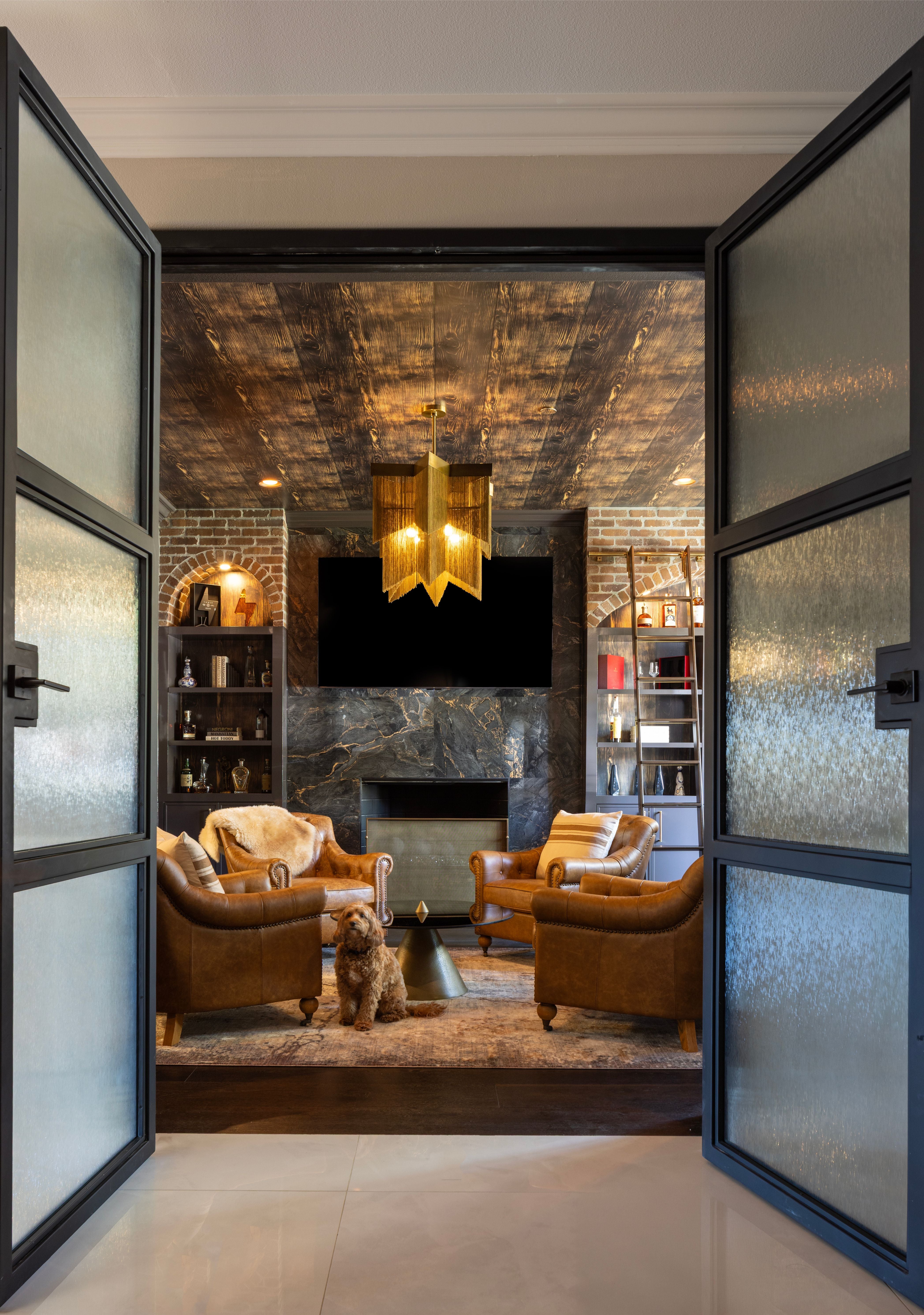 Modern living room with open doors leading to a stylish interior with a doodle dog posing in the center. 