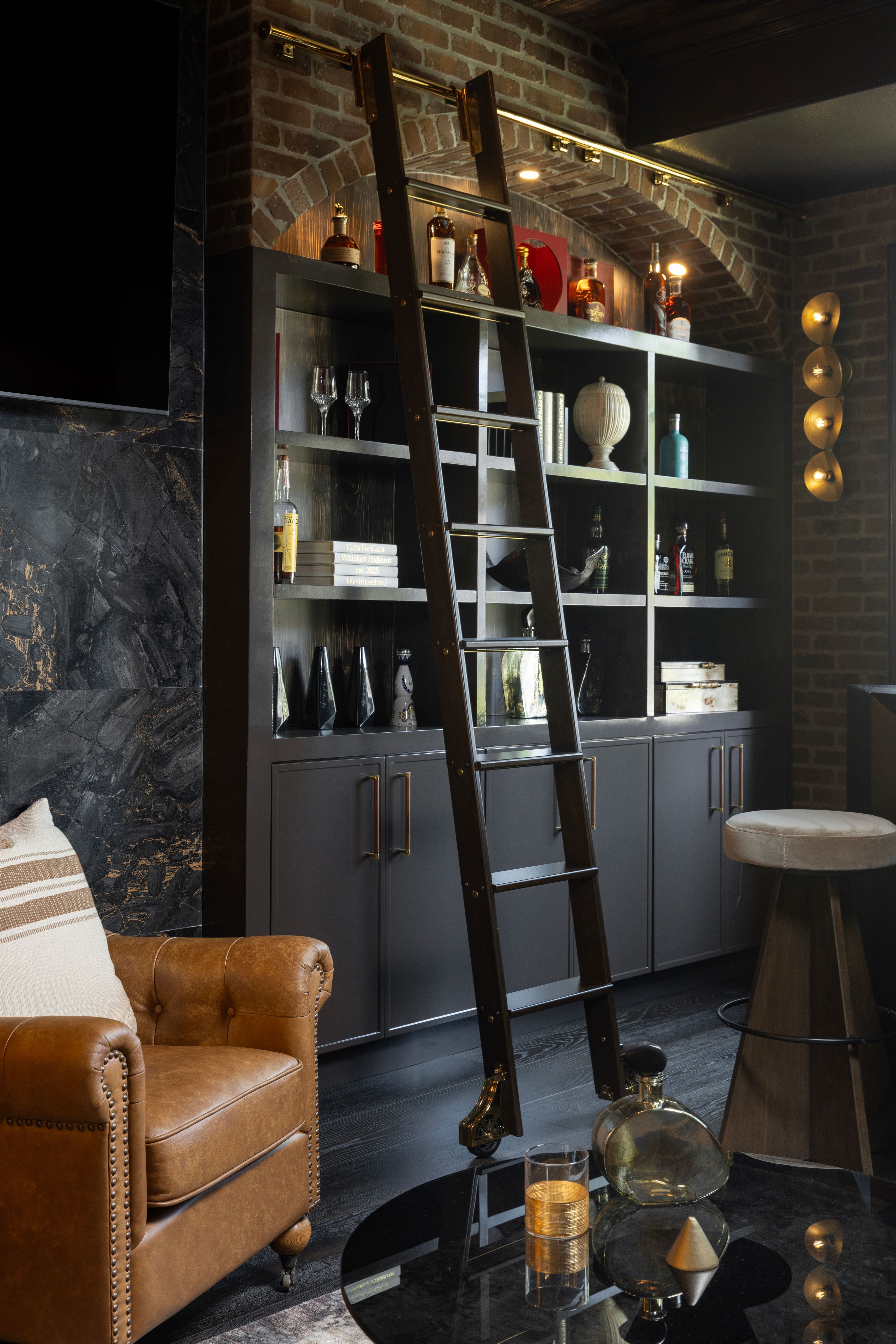 Modern living room with a bookshelf and ladder, a brown armchair, and decorative items.