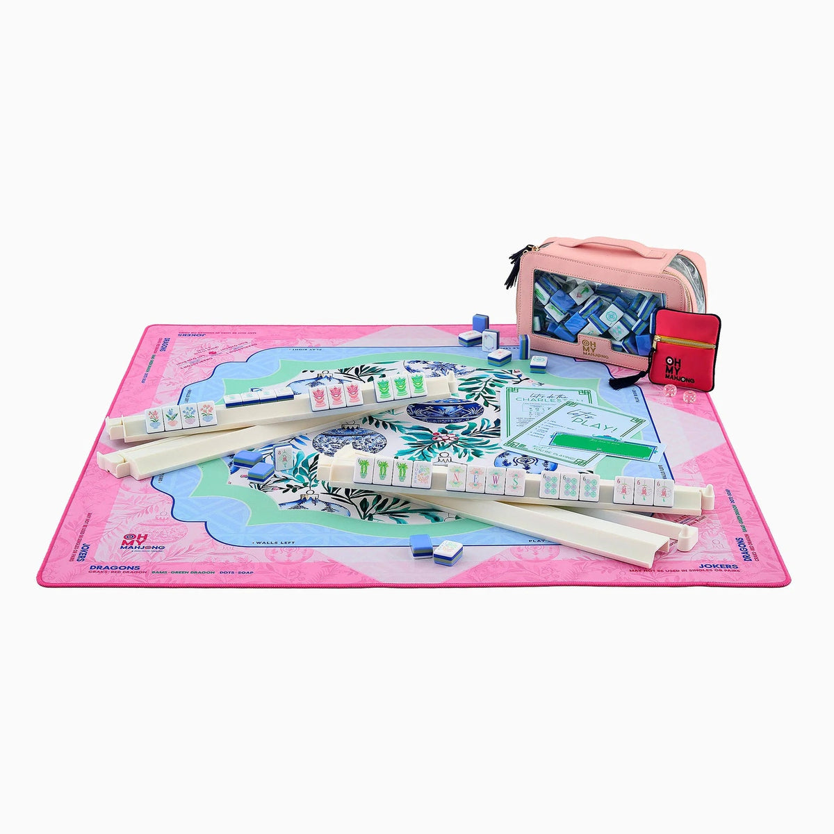 A pink and blue mahjong set displayed on a white background, including a large game board, multiple racks of tiles, a pink carrying case, and a small red accessory.